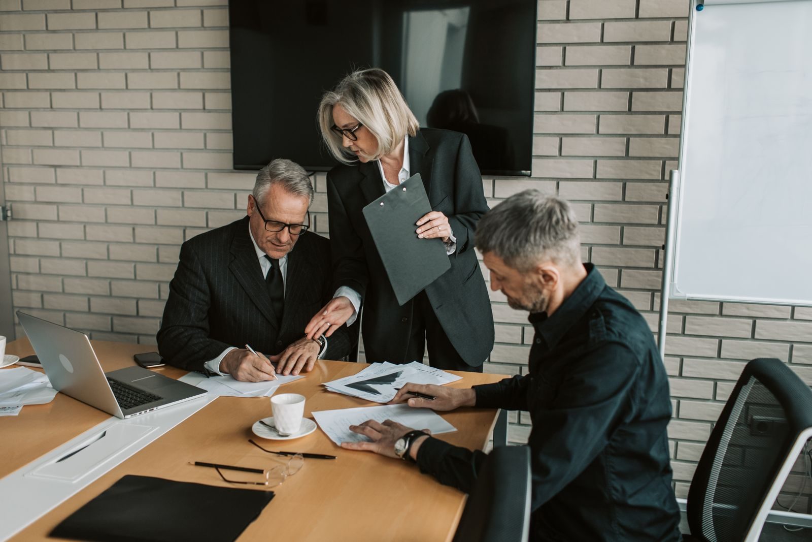Senior professionals reviewing documents together in a boardroom meeting