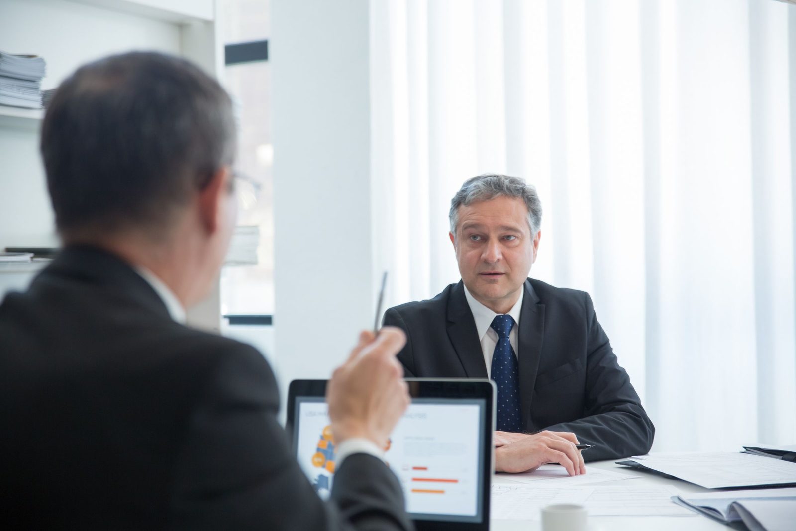 Two senior executives in a focused one to one conversation across a desk