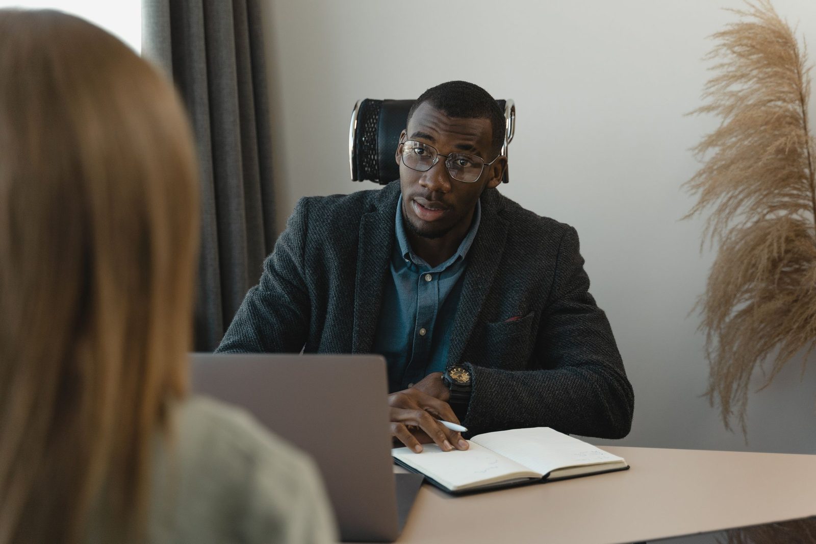 A senior leader in a one to one review conversation across a desk with a notebook open