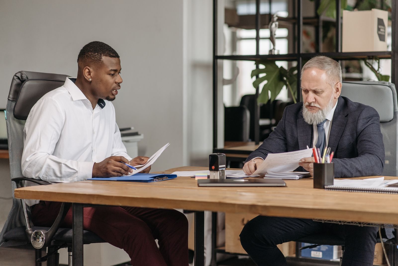 Two executives reviewing documents across a desk during a one to one working session
