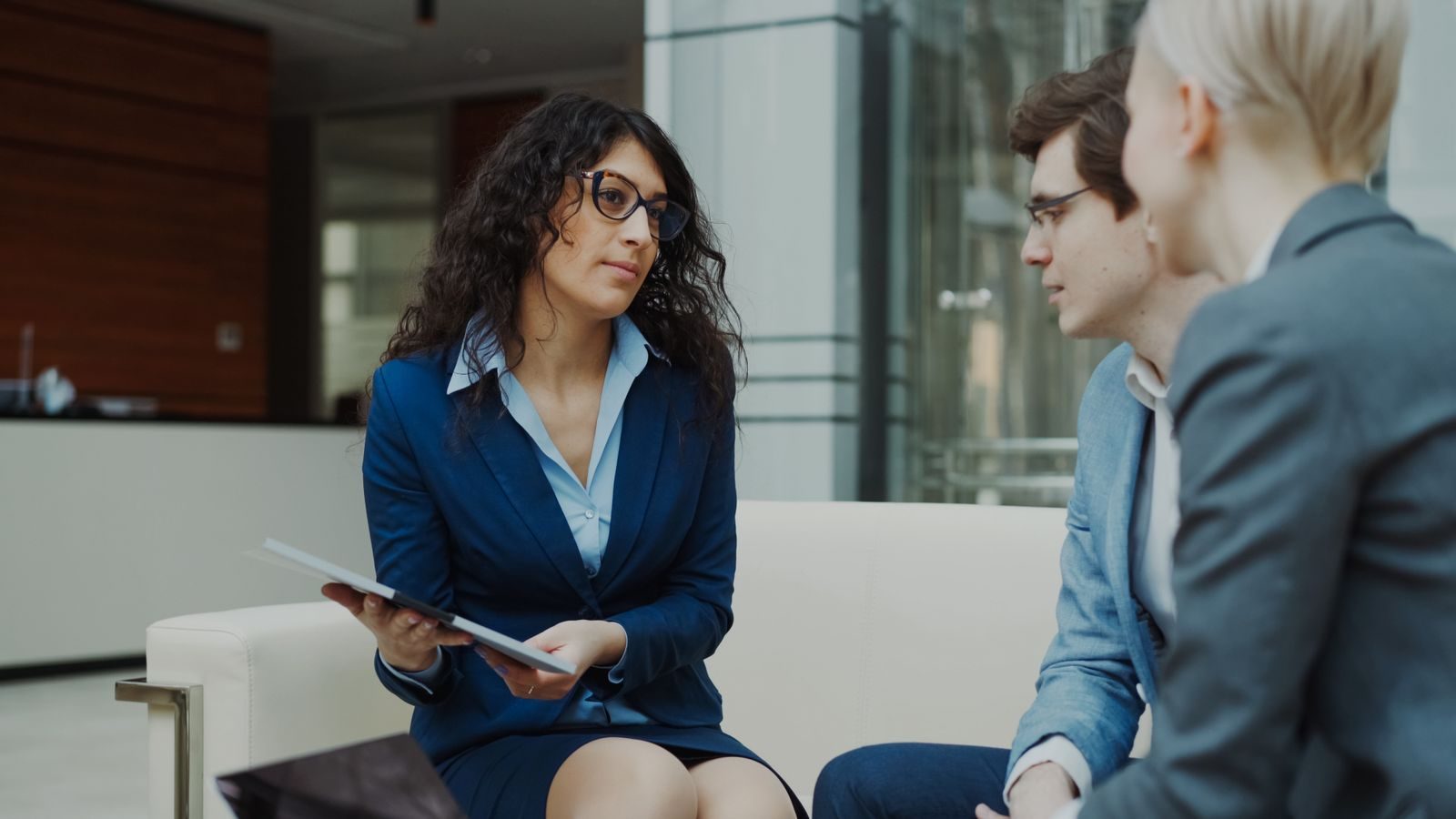 Three senior professionals in a candid working conversation in a corporate lobby