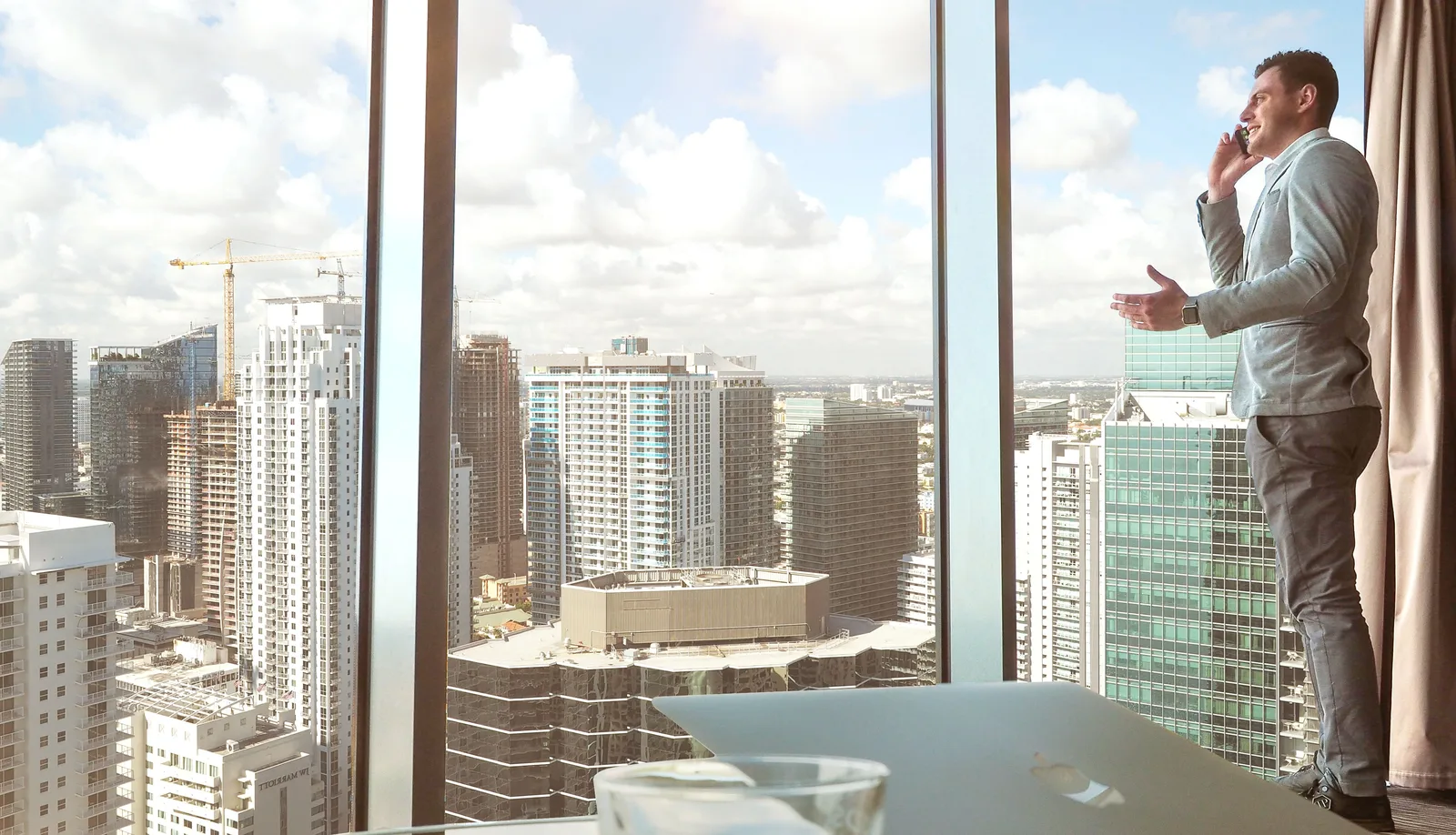 Executive taking a call in a high-rise office overlooking the city skyline below